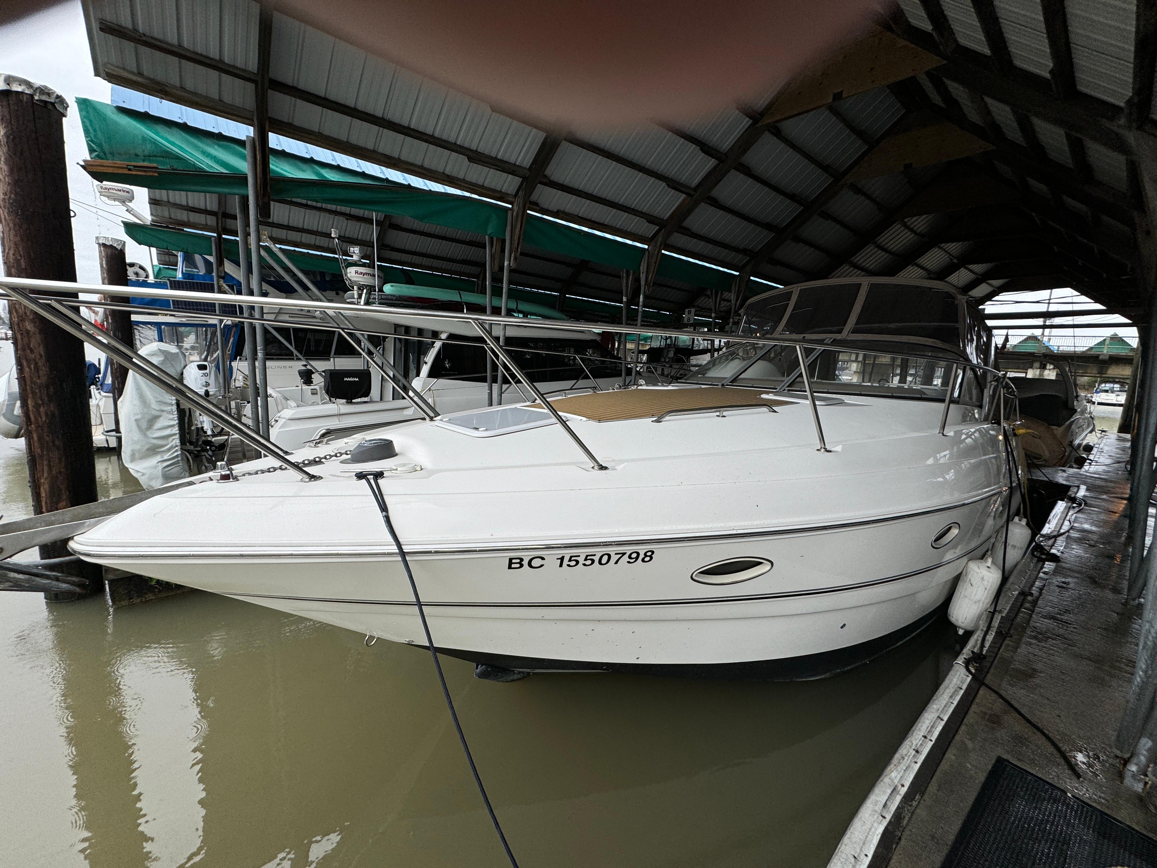 2003 Larson 330 Cabrio boat docked under a covered marina.
