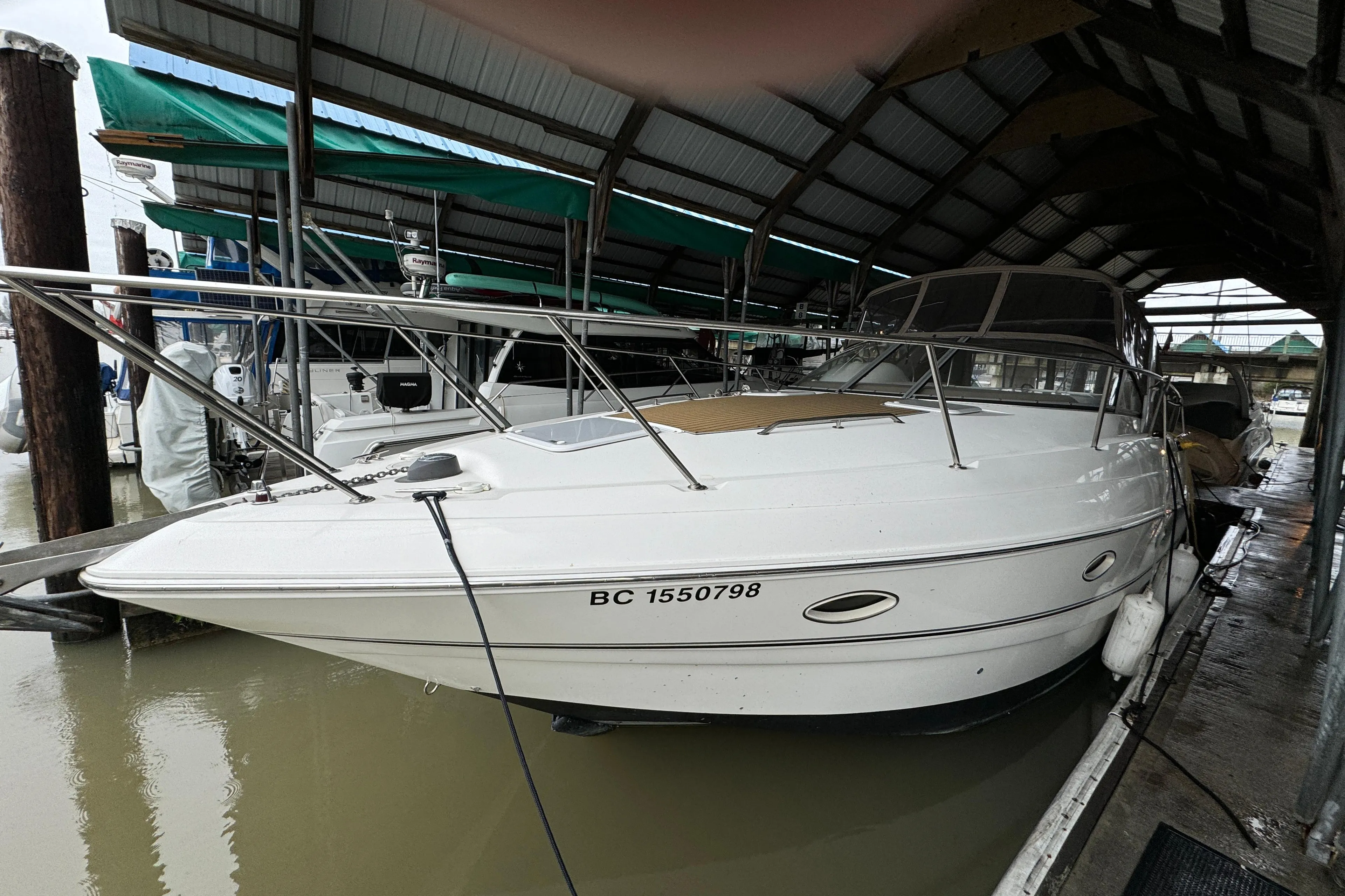 2003 Larson 330 Cabrio boat docked under a covered marina.
