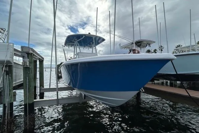  Yacht Photos Pics 2023 Contender 28 Tournament boat in blue, docked on a lift under cloudy skies.