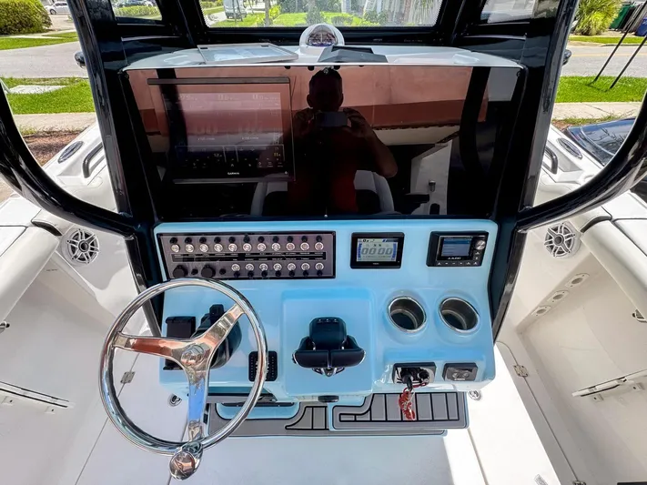  Yacht Photos Pics 2024 Tidewater 256 Adventurer boat dashboard with steering wheel and control panel.