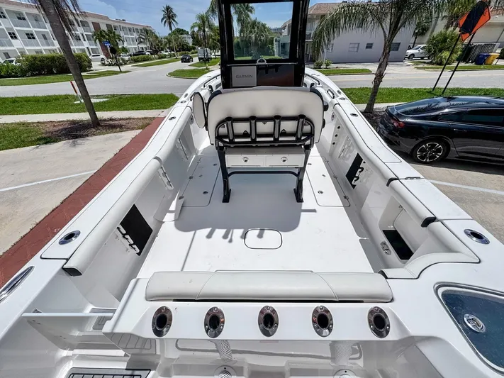  Yacht Photos Pics 2024 Tidewater 256 Adventurer boat interior with seating and rod holders, parked near palm trees.