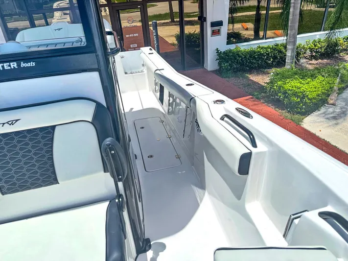  Yacht Photos Pics 2024 Tidewater 256 Adventurer boat interior with seating and storage, displayed outdoors.