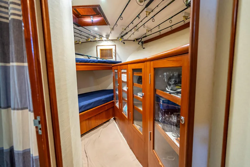 Andiamo Yacht Photos Pics 1979 Merritt 46 yacht cabin with wooden cabinets and fishing rods.