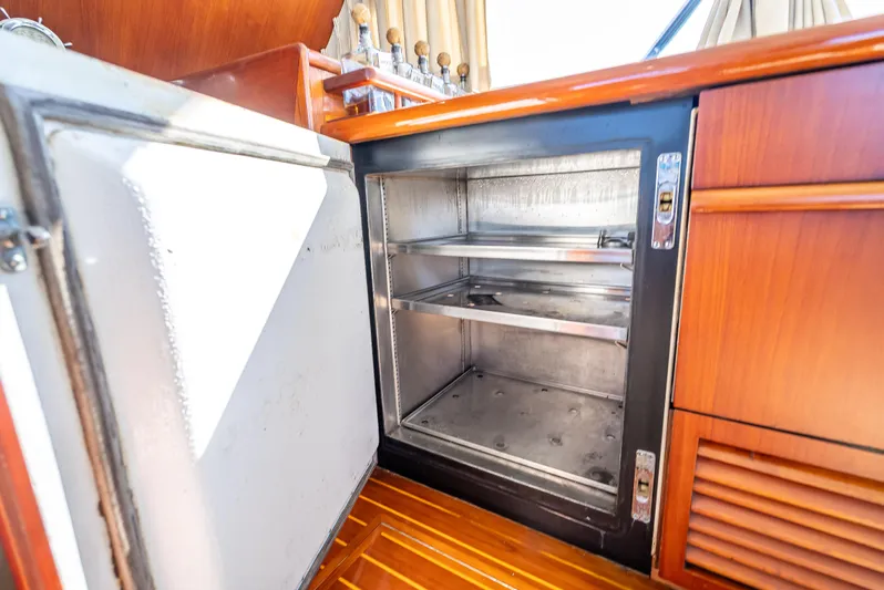 Andiamo Yacht Photos Pics Open refrigerator in 1979 Merritt 46 yacht with wooden cabinetry.