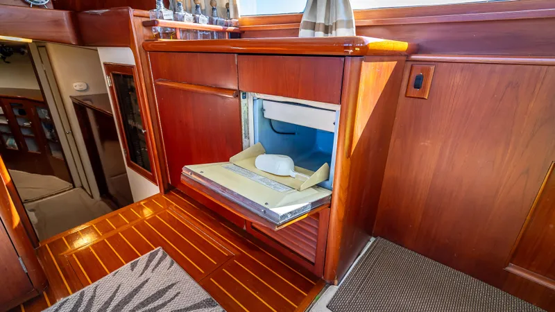 Andiamo Yacht Photos Pics 1979 Merritt 46 yacht interior with wooden cabinetry and built-in refrigerator.