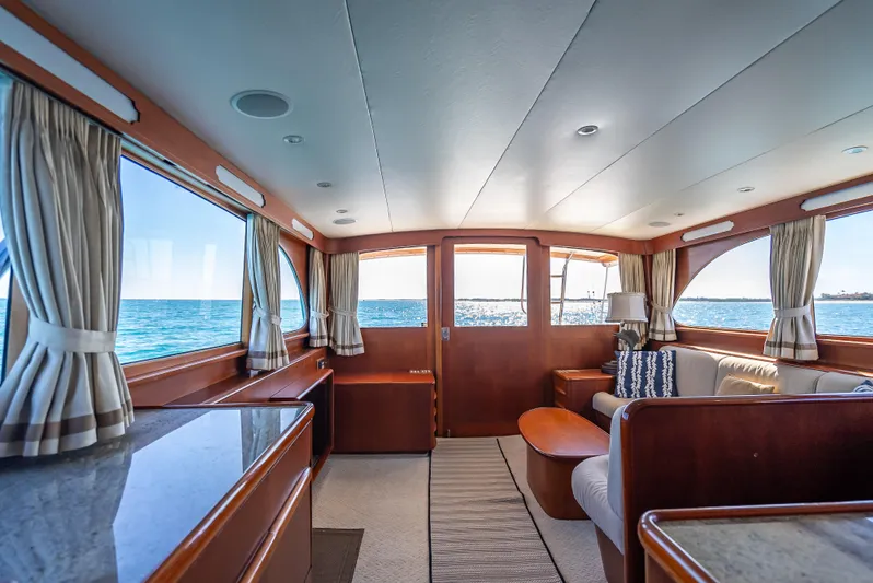 Andiamo Yacht Photos Pics Luxurious 1979 Merritt 46 yacht interior with ocean view, featuring elegant wood finishes and cozy seating.