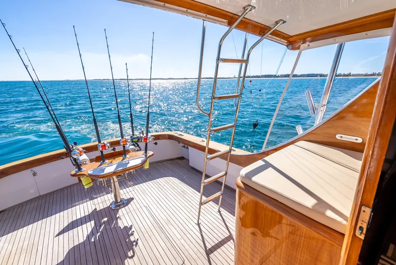 Andiamo Yacht Photos Pics 1979 Merritt 46 yacht deck with fishing rods, ocean view, and ladder.
