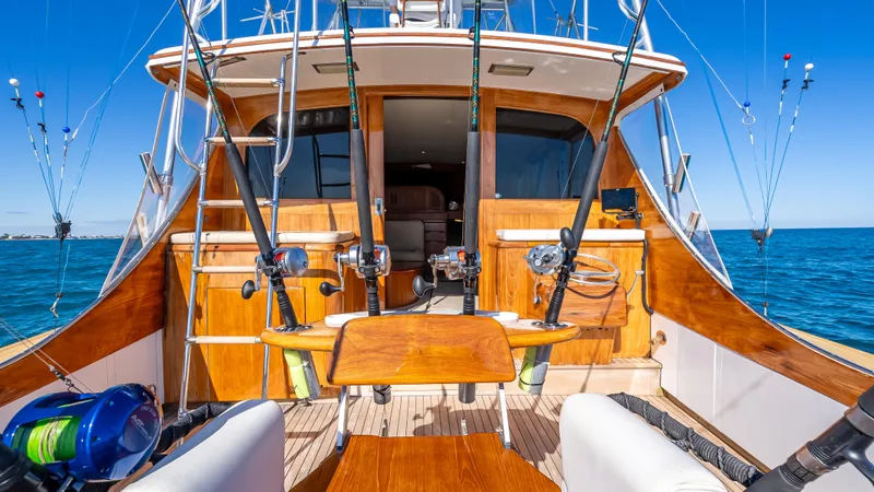 Andiamo Yacht Photos Pics 1979 Merritt 46 yacht with fishing rods, wooden deck, and ocean backdrop.