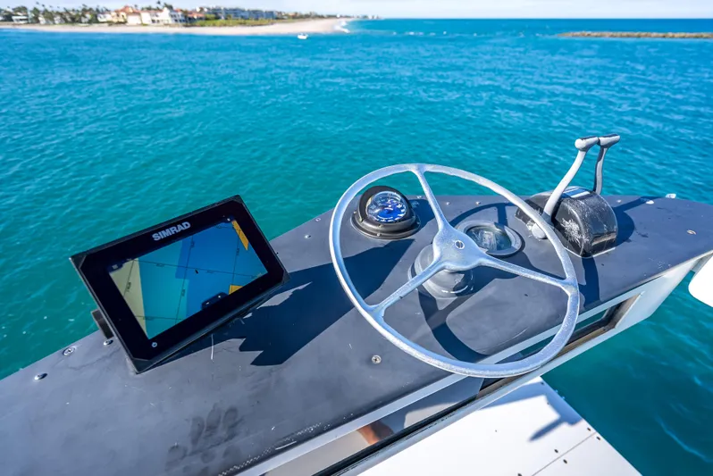 Andiamo Yacht Photos Pics Steering wheel and navigation system on 1979 Merritt 46 boat, overlooking blue ocean waters.
