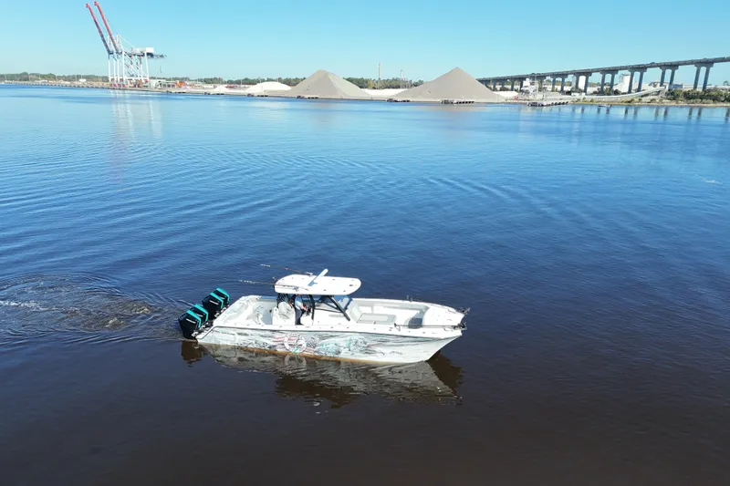  Yacht Photos Pics 2024 Front Runner 37 Catamaran cruising on a calm river with industrial backdrop.