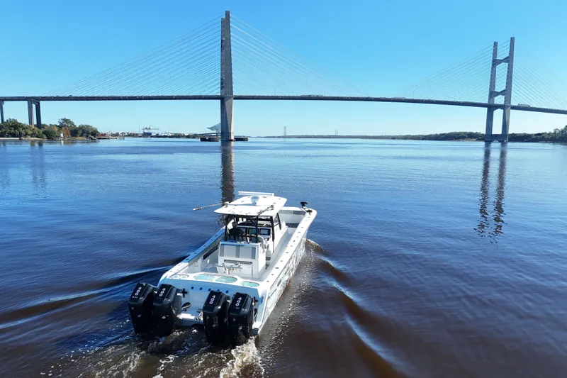  Yacht Photos Pics 2024 Front Runner 37 Catamaran cruising under a large suspension bridge on a sunny day.
