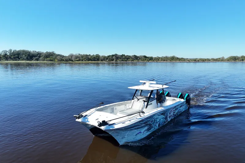  Yacht Photos Pics 2024 Front Runner 37 Catamaran cruising on a serene lake under a clear blue sky.