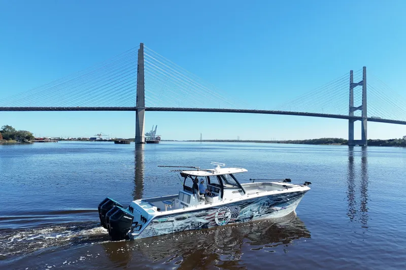  Yacht Photos Pics 2024 Front Runner 37 Catamaran cruising under a large suspension bridge on a sunny day.