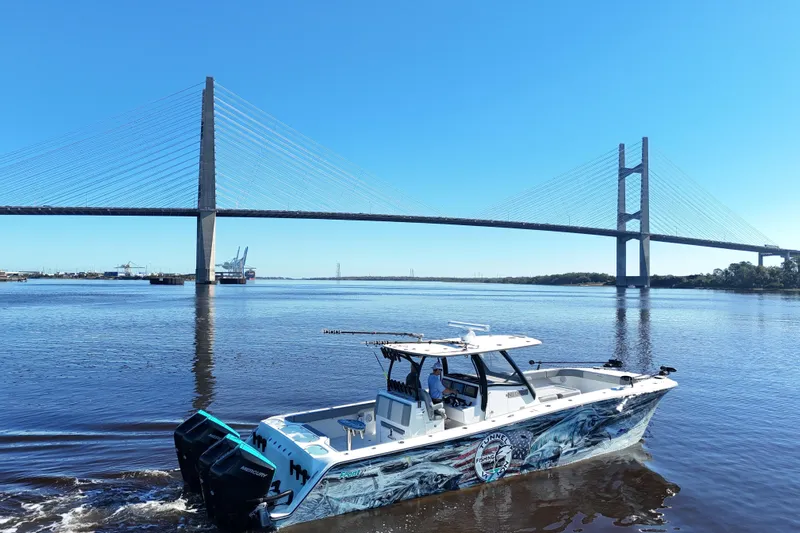  Yacht Photos Pics 2024 Front Runner 37 Catamaran cruising under a large suspension bridge on a sunny day.