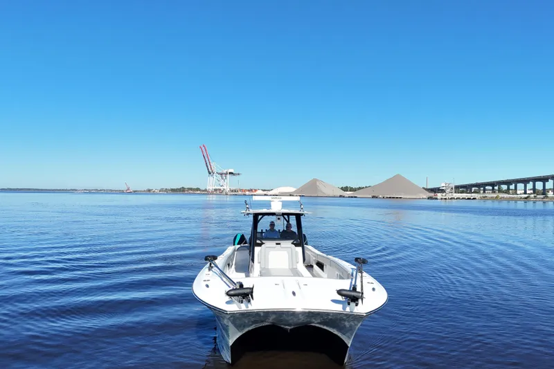  Yacht Photos Pics 2024 Front Runner 37 Catamaran on calm water with industrial backdrop.