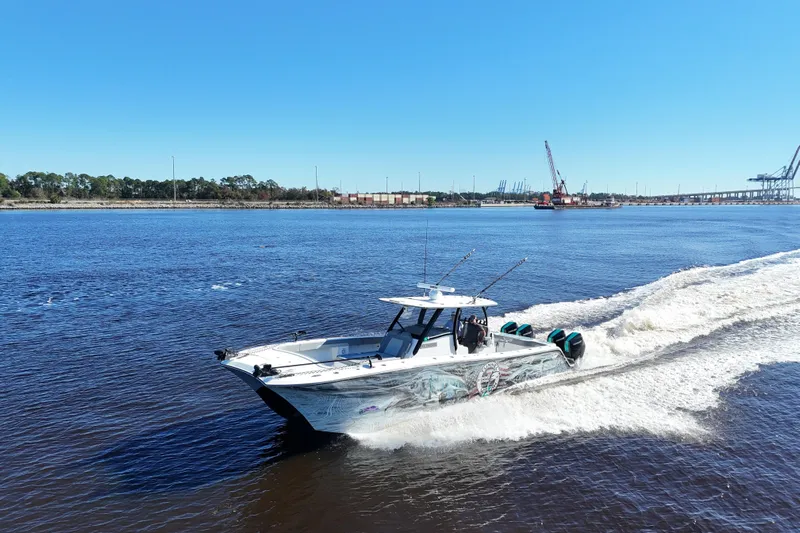  Yacht Photos Pics 2024 Front Runner 37 Catamaran cruising on a sunny day near industrial docks.