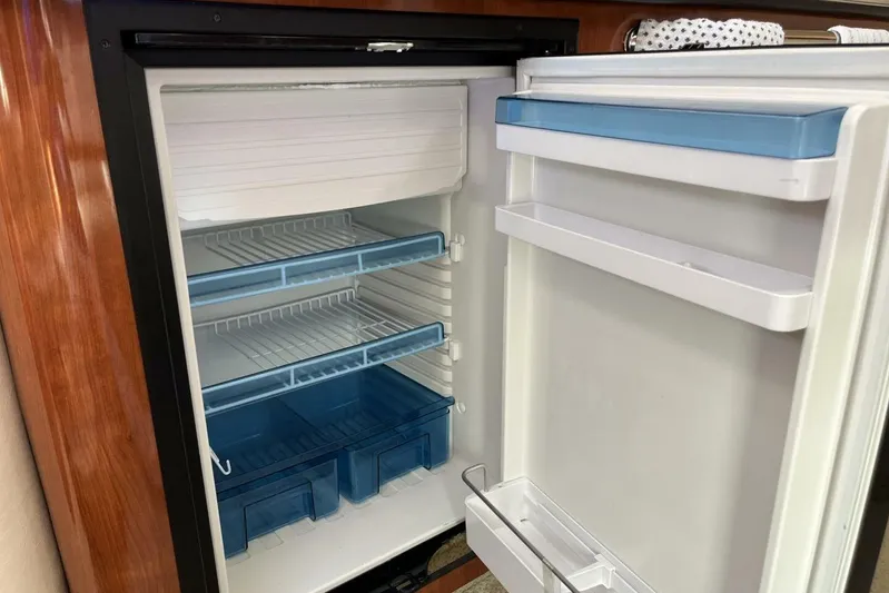  Yacht Photos Pics Open refrigerator inside 2007 Sea Ray 340 Sundancer yacht, featuring blue shelves and drawers.