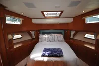 Luxurious cabin interior of 2010 Trader 64 Sunliner yacht with cozy bed and wooden furnishings.