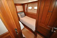 Cozy cabin interior of 2010 Trader 64 Sunliner yacht with wooden furnishings and single bed.
