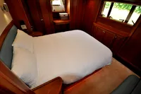 Luxurious cabin interior of 2010 Trader 64 Sunliner yacht with cozy bed and wooden furnishings.