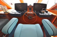 Cockpit of 2010 Trader 64 Sunliner yacht with modern controls and wooden steering wheel.