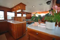 Luxurious interior of 2010 Trader 64 Sunliner yacht with elegant wood cabinetry and potted plants.