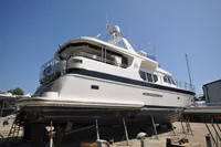 Luxurious 2010 Trader 64 Sunliner yacht on dry dock under clear blue sky.