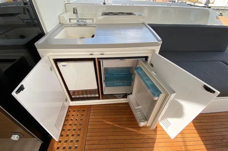  Yacht Photos Pics Outdoor kitchenette on 2022 Lagoon 50 yacht with sink and open mini fridge.