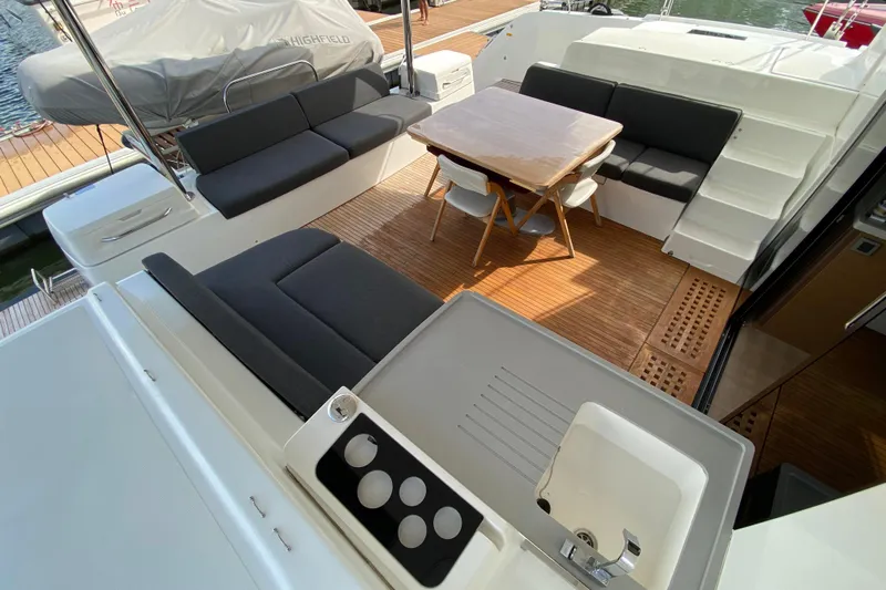  Yacht Photos Pics Luxurious 2022 Lagoon 50 yacht interior with seating, table, and sink on teak deck.