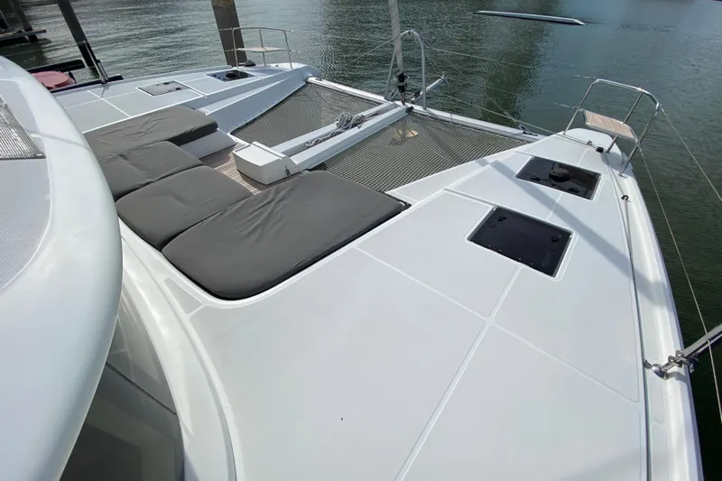  Yacht Photos Pics 2022 Lagoon 50 catamaran deck with cushioned seating and netting over water.