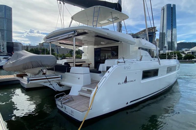  Yacht Photos Pics 2022 Lagoon 50 yacht docked in urban marina with city skyline backdrop.