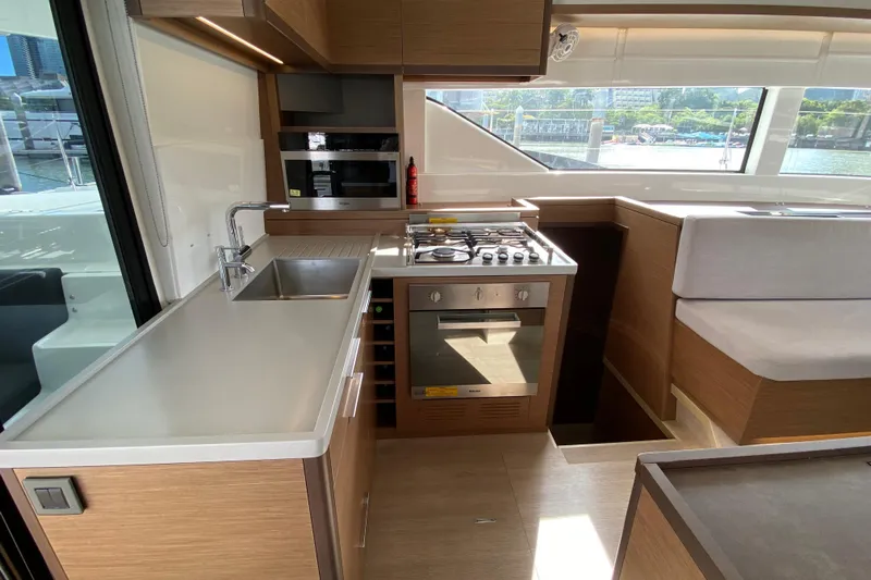  Yacht Photos Pics Modern kitchen interior of 2022 Lagoon 50 yacht with stove, sink, and seating area.