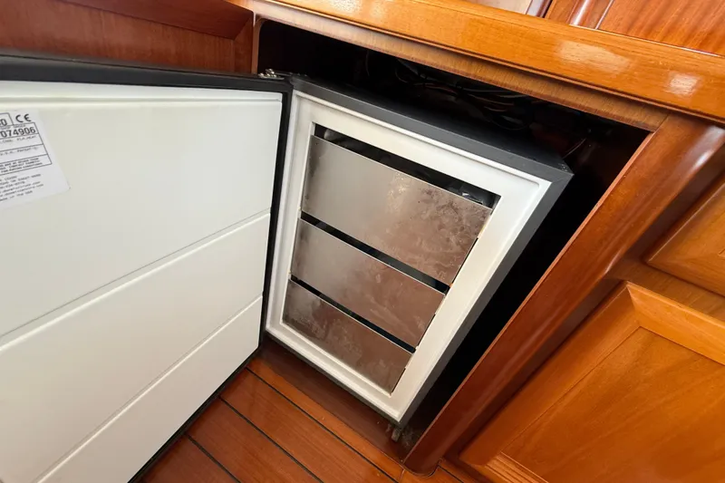 All At Sea Yacht Photos Pics Open refrigerator in 2007 Beneteau Swift Trawler 42, showcasing wooden interior cabinetry.