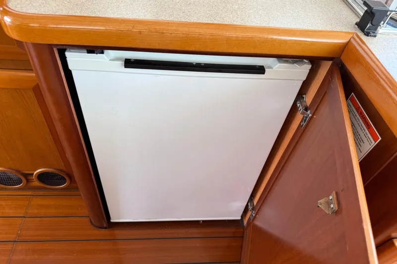 All At Sea Yacht Photos Pics 2007 Beneteau Swift Trawler 42 interior with open wooden cabinet and built-in refrigerator.