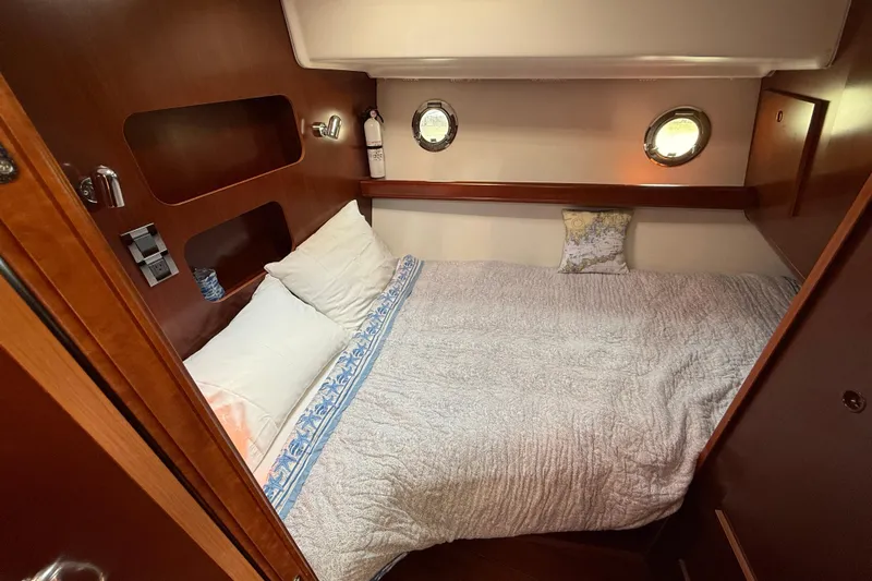 All At Sea Yacht Photos Pics Cozy cabin interior of 2007 Beneteau Swift Trawler 42 with portholes and comfortable bedding.