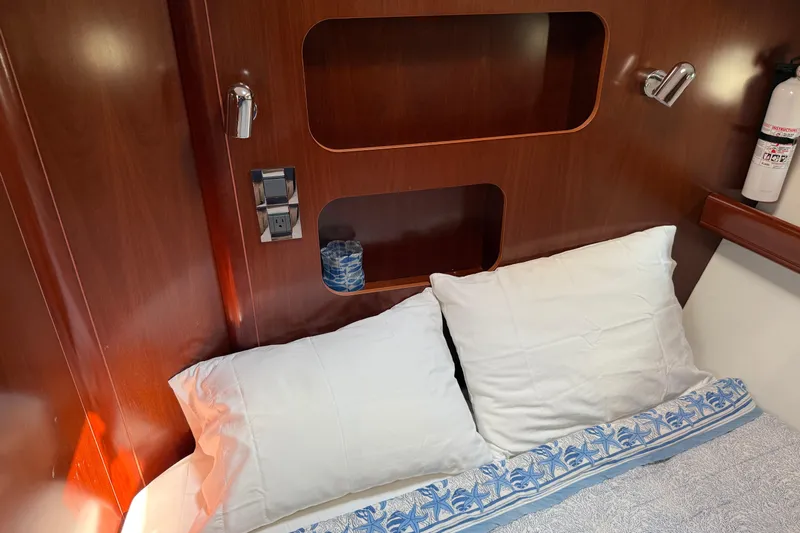All At Sea Yacht Photos Pics Cozy cabin interior of 2007 Beneteau Swift Trawler 42 with pillows and wooden shelving.