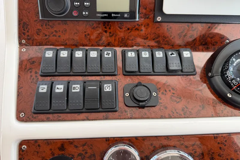 All At Sea Yacht Photos Pics Control panel of a 2007 Beneteau Swift Trawler 42 with various switches and a compass.