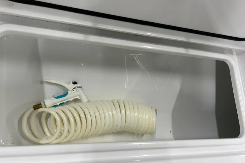  Yacht Photos Pics Coiled hose and spray nozzle in Contender 24 Sport boat compartment, 2024 model.