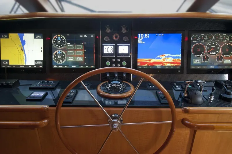 Compass Rose Yacht Photos Pics Control panel of a 1995 Custom Heisley boat with navigation screens and steering wheel.