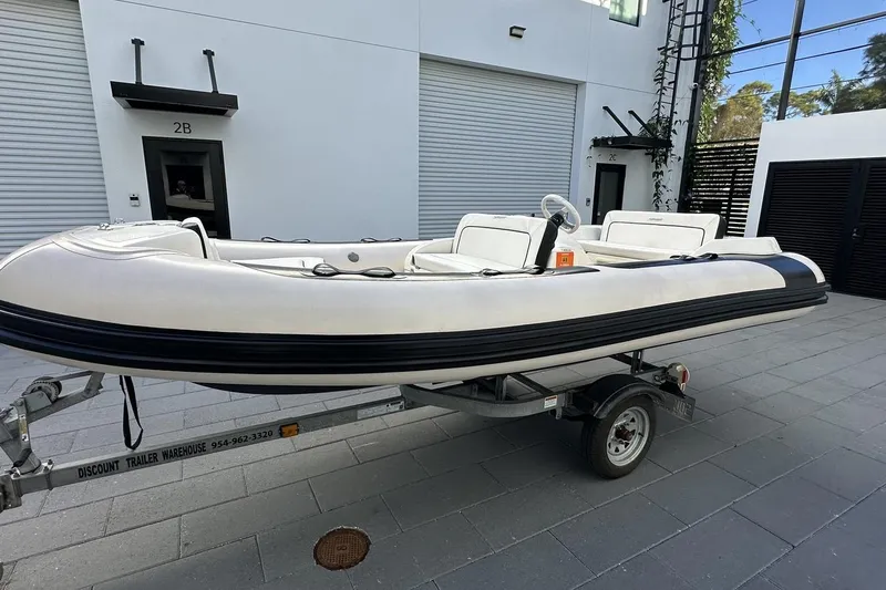 Compass Rose Yacht Photos Pics Custom 1995 Heisley inflatable boat on trailer, parked outside modern building.