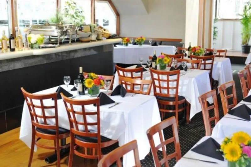 Klancy II Yacht Photos Pics Elegant restaurant interior with white tablecloths, wooden chairs, and vibrant floral centerpieces.