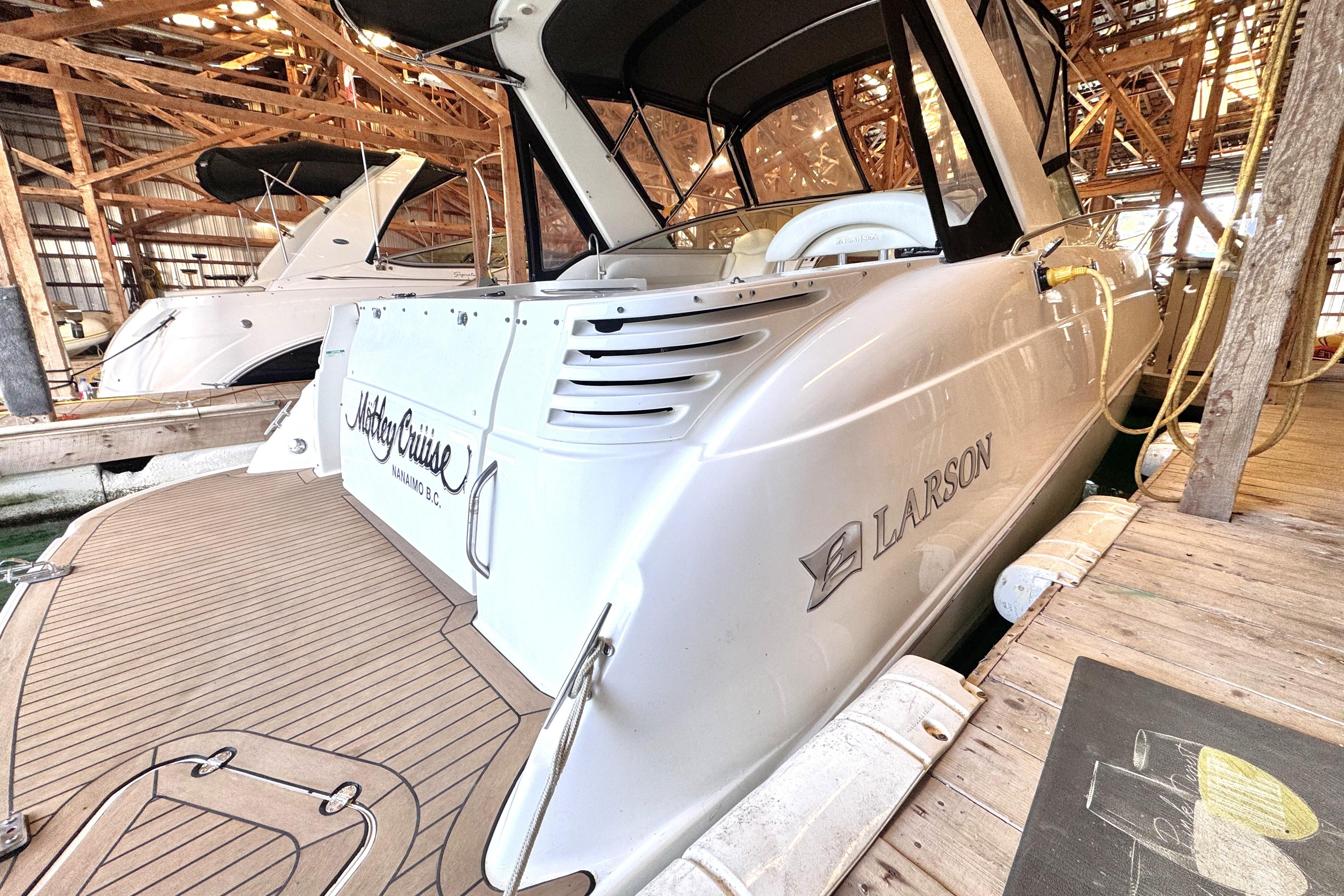 2002 Larson Cabrio 310 boat docked in a wooden marina, showcasing sleek design and branding.