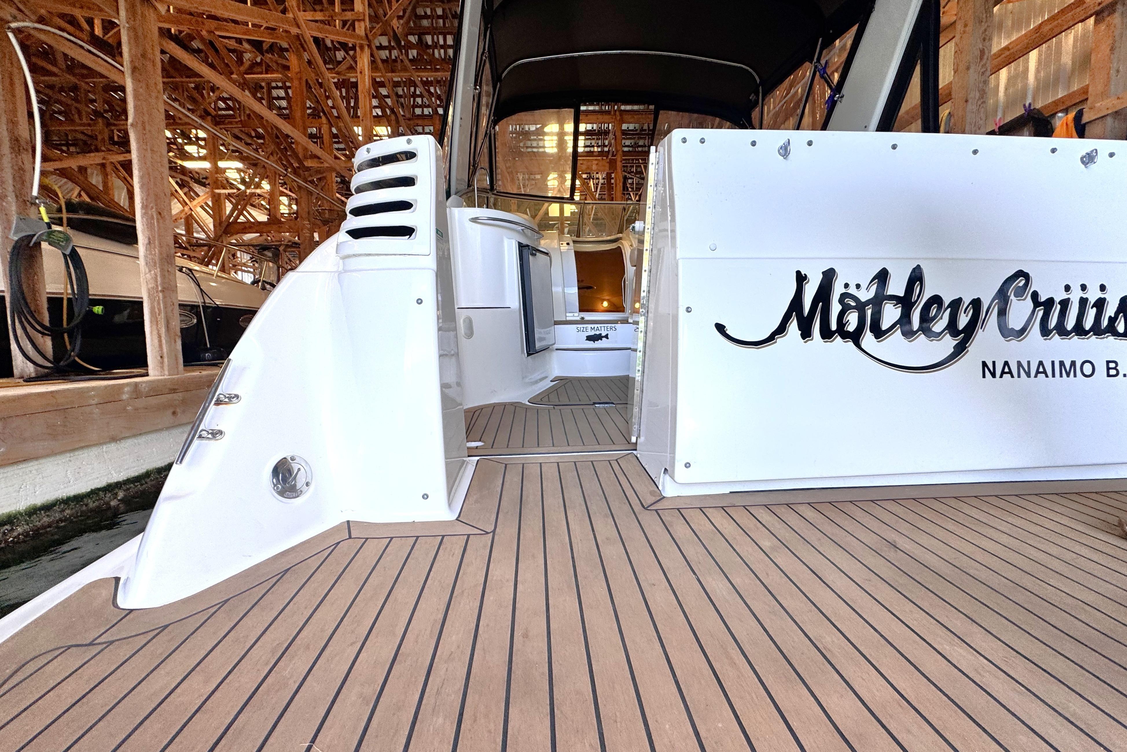 2002 Larson Cabrio 310 boat docked, featuring teak deck and custom lettering.