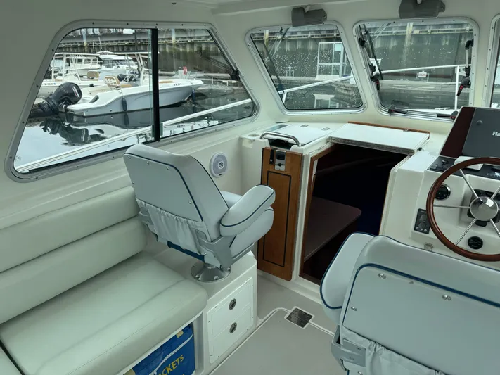 Change Of Pace Yacht Photos Pics 2008 Back Cove 29 Hardback boat interior with helm, seating, and windows overlooking marina.