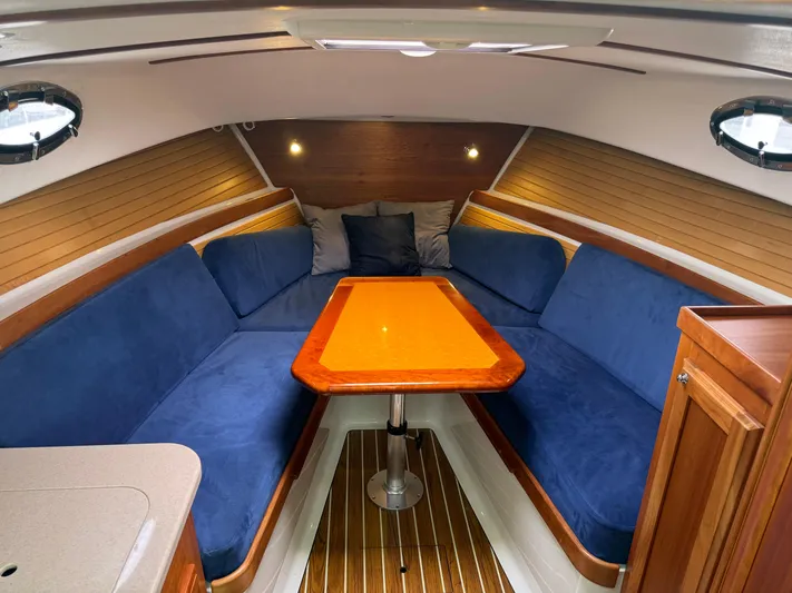 Change Of Pace Yacht Photos Pics 2008 Back Cove 29 Hardback interior with blue seating and wooden table.