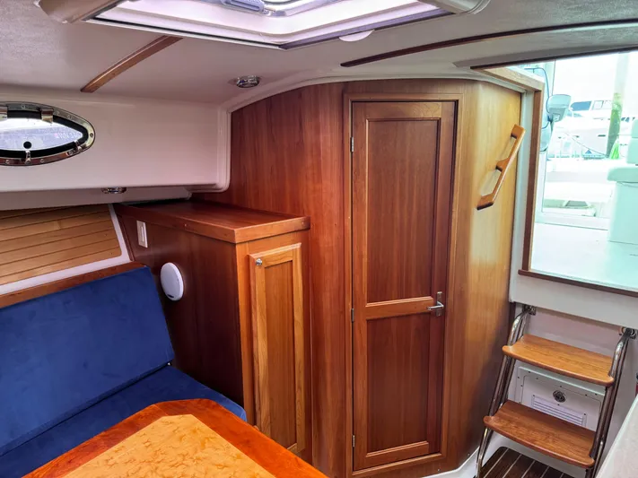Change Of Pace Yacht Photos Pics Interior of 2008 Back Cove 29 Hardback boat with wooden cabinetry and blue seating.
