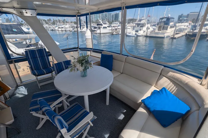 Fisher Folly IV Yacht Photos Pics 1988 Offshore Yachts 48 Yachtfisher interior with seating, table, and marina view.