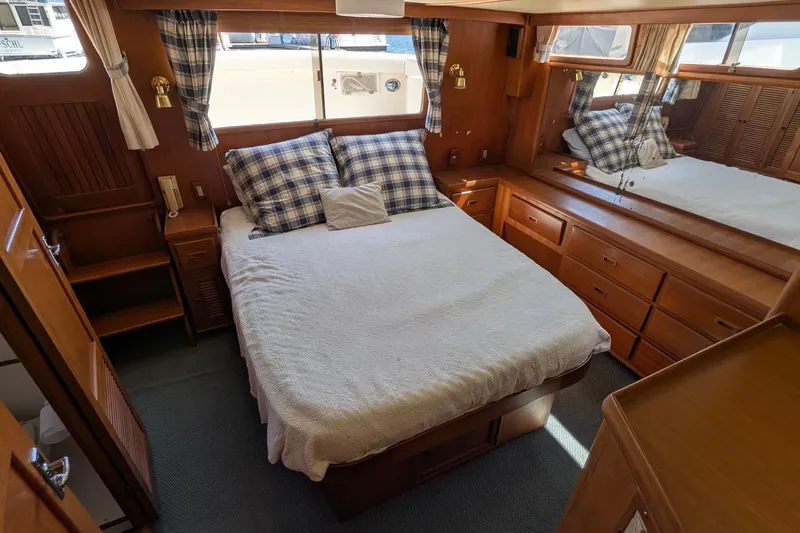 Fisher Folly IV Yacht Photos Pics 1988 Offshore Yachts 48 Yachtfisher cabin with cozy bed, wooden furnishings, and nautical decor.