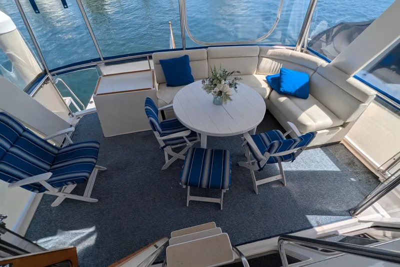 Fisher Folly IV Yacht Photos Pics Luxurious seating area on 1988 Offshore Yachts 48 Yachtfisher with blue accents and round table.