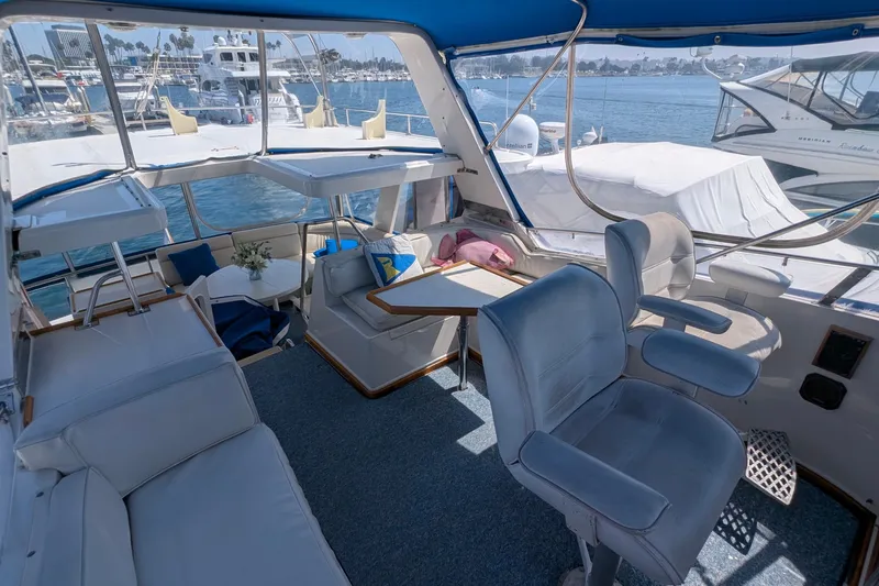 Fisher Folly IV Yacht Photos Pics 1988 Offshore Yachts 48 Yachtfisher interior with seating, table, and marina view.